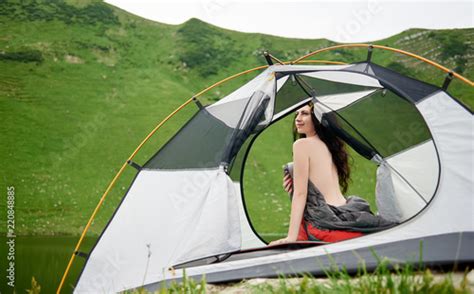 back view of beautiful naked woman traveller sitting in tent in