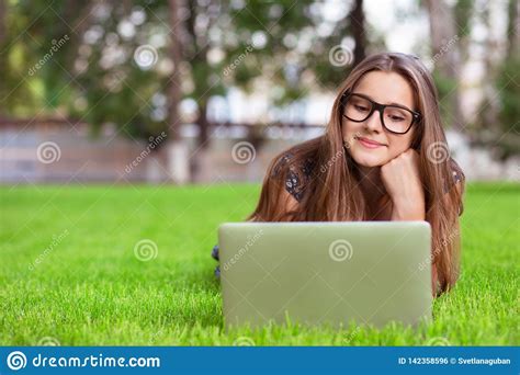 woman in glasses sitting in a public garden while using her laptop