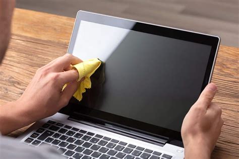 man cleaning laptop screen soft yellow   clean laptop screen ss
