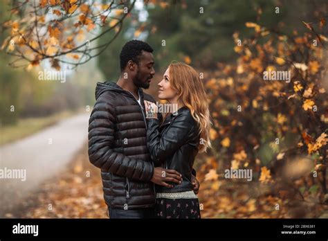 happy cute interracial couple posing in blurry autumn park background