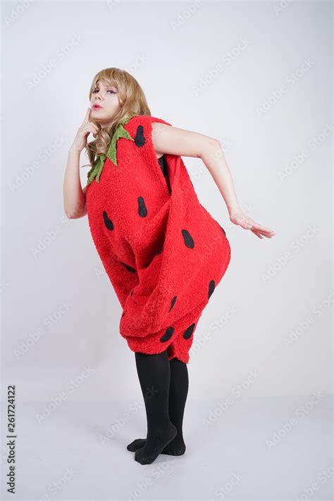 Caucasian Emotive Blonde Girl In A Huge Plush Suit Of Red Strawberry Is