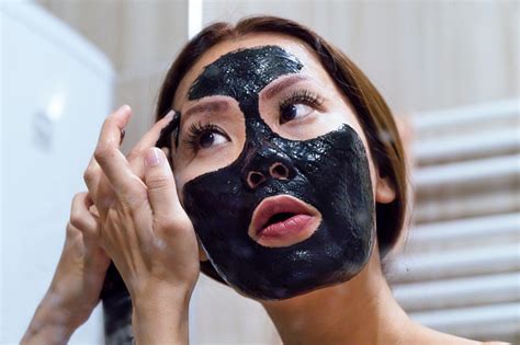 portrait of woman peeling off pulling off her charcoal black facial