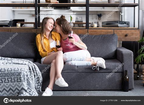 Two Lesbians Holding Wine Glasses While Sitting Sofa Living Room Stock