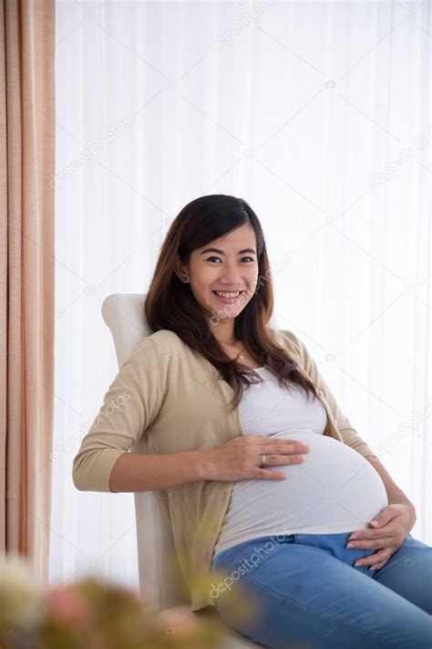 Front View Of Pregnant Japanese Woman With Hands On Stomach High Res