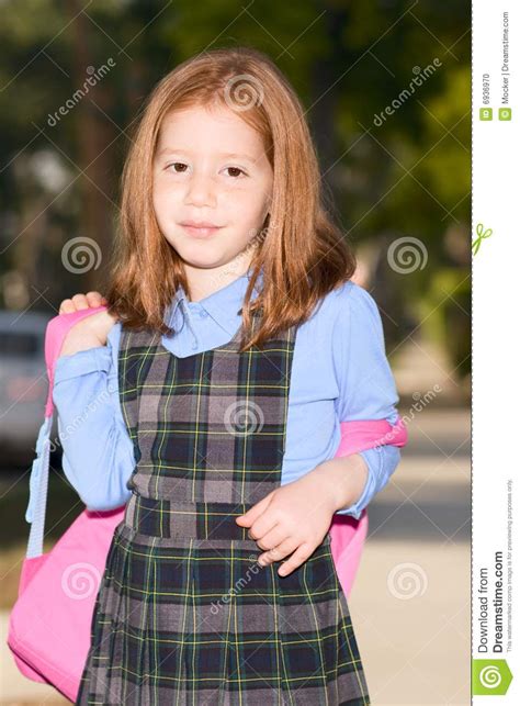 elementary age schoolgirl in uniform with backpack stock