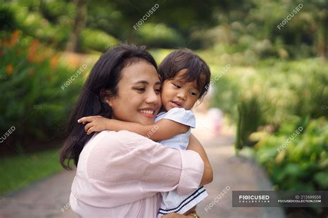 cute asian mother and daughter hugging in park — woman
