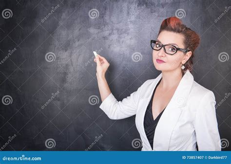 Beautiful Teacher With Piece Of Chalk On Blackboard Background Royalty
