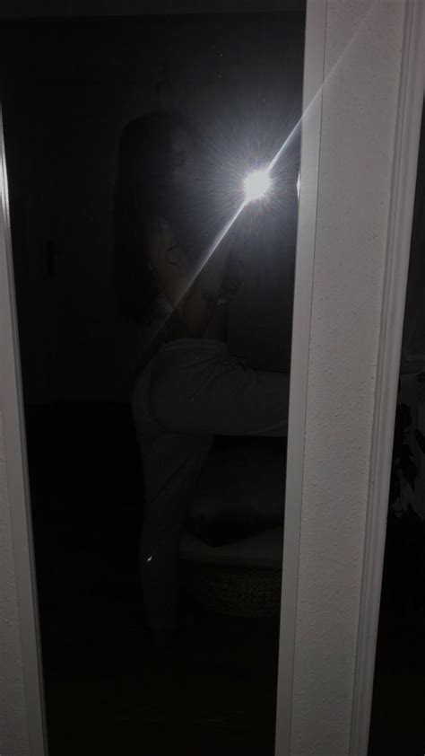 a woman taking a selfie in the mirror with her cell phone at night time