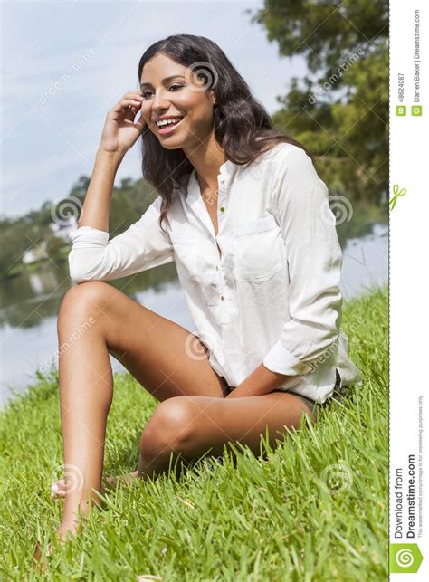latina woman girl sitting on grass by lake in summer stock