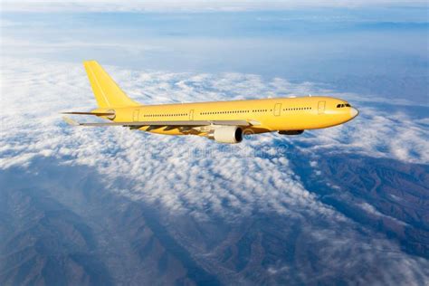 yellow passenger plane  flying   clouds side view  aircraft stock photo image