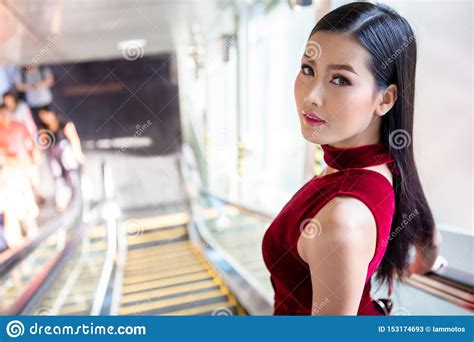 Beautiful Young Asian Woman In Red Dress Going Down The Escalator In