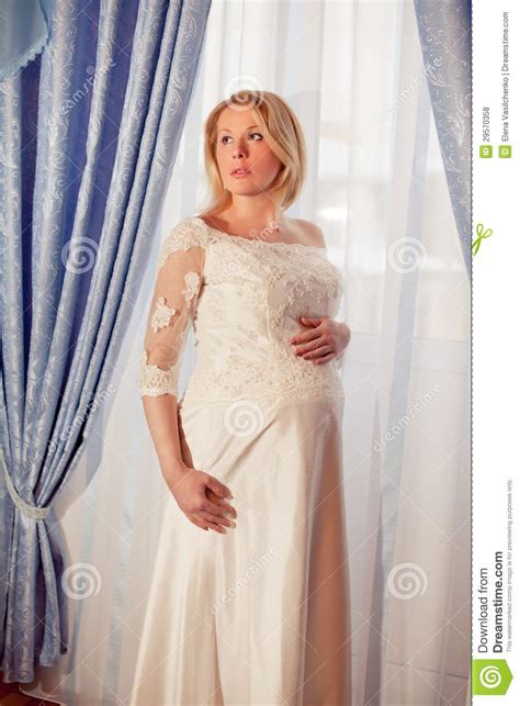 beautiful pregnant bride posing against window royalty