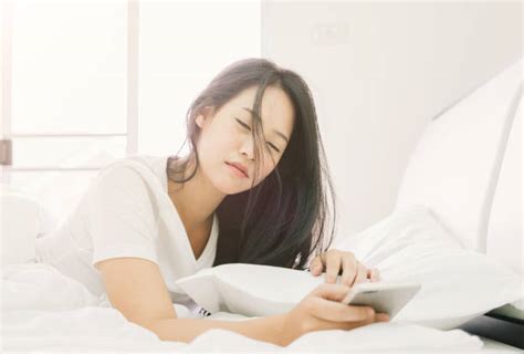 royalty free girl on bed snoozing mobile phone alarm