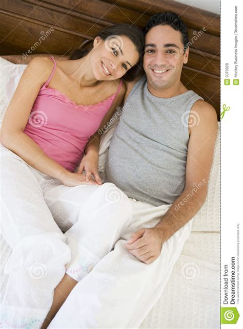 a middle eastern couple lying on a bed royalty free stock