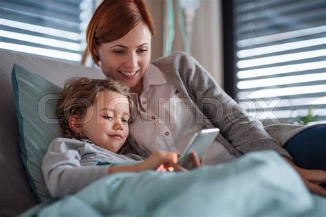 happy small girl with mother in bed in stock image colourbox