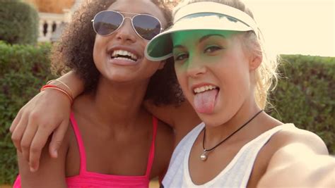selfie style portrait of two two teen girl friends sticking their tongues out at the camera 스톡
