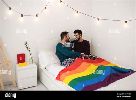 Gay Men Couple Having Tender Moments Sitting On Bed At Home