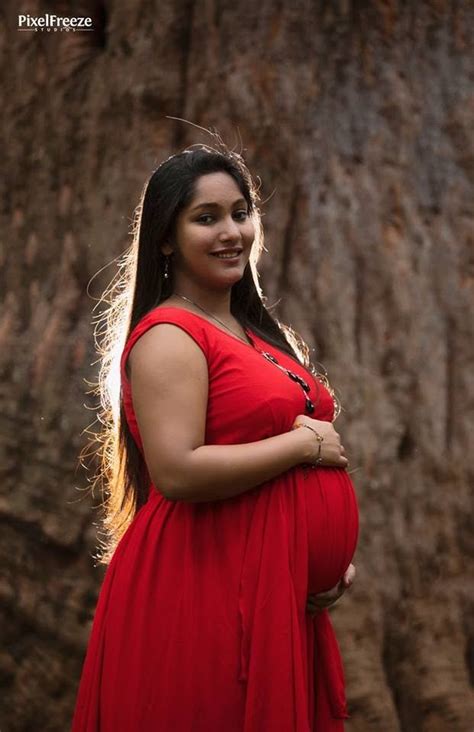 A Pregnant Woman Standing In Front Of A Tree