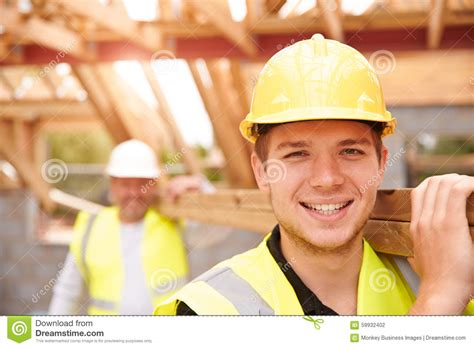 builder  apprentice carrying wood  construction site stock photo