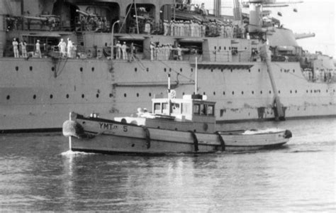 as mighty a warship as there ever was yard motor tug 5 passes the uss nevada bb 36 at naval