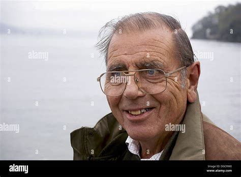 headshot of a 75 year old man smiling off camera with the sea behind