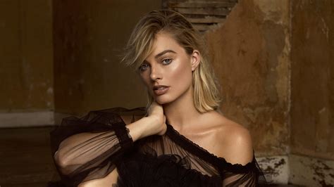 Margot Robbie Is Sitting On Floor Wearing Black Top With A Wall