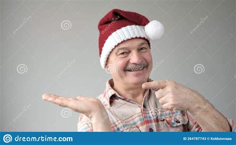 friendly looking attractive european pensioner in red santa claus hat