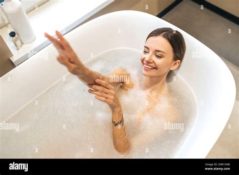 top view of a smiling beautiful woman lying in the bathtub filled with