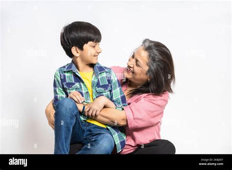 Happy Indian Grandmother And Grandson Hug Sit On Floor Look At Each