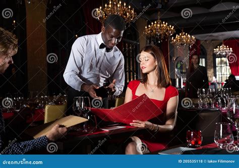 Polite African American Waiter Bringing Ordered Dishes To Couple At