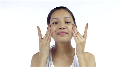 beautiful girl rubbing moisturizer on her face using her hands