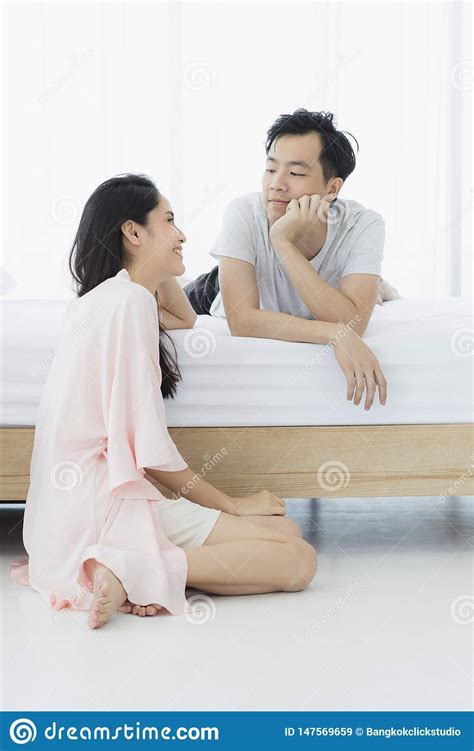 asian couple in pajamas sit in bedroom stock image image