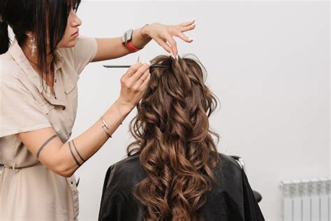 cabeleireiro em um salão de beleza faz um penteado para uma noiva com