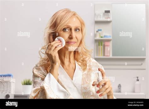Mature Woman Cleaning Her Face With A Cotton Pad And Face Tonic Inside