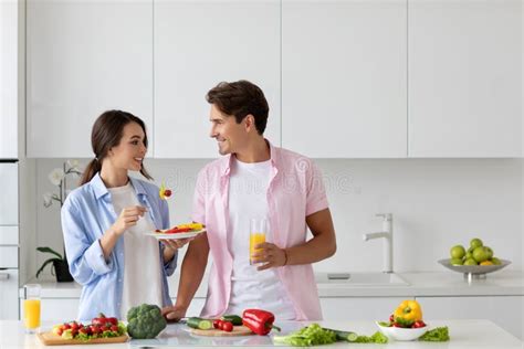 woman feeding her man tasting healthy vegetable salad in the kitchen