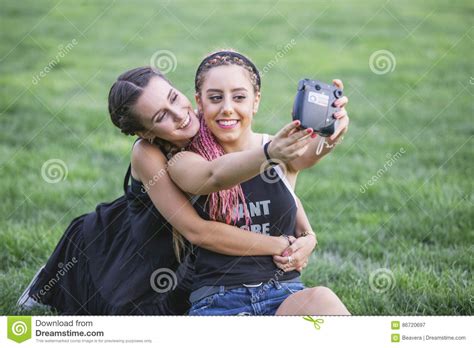 two teen girlfriends taking a photo with a camera stock