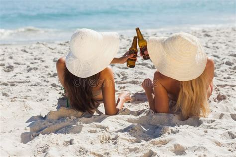 Attractive Blonde And Brunette In Bikinis Clinking Glass Bottles Stock