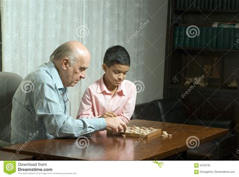 grandfather and grandson sitting at table playing stock