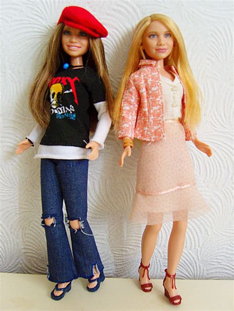 two barbie dolls standing next to each other on a white surface with a