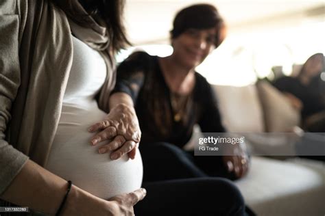 Senior Woman Touching Pregnant Daughters Belly At Home High Res Stock
