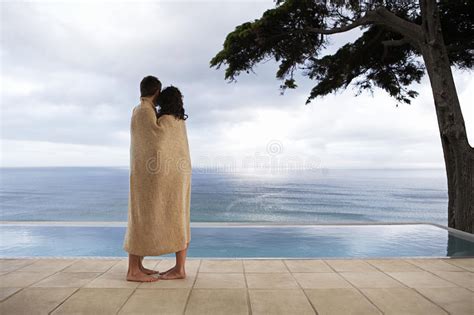 Couple Relaxing On Sunbeds By Infinity Pool Stock Image