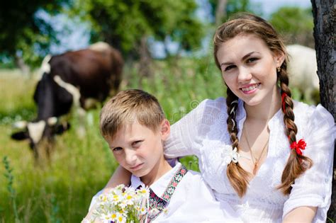teen sister and little brother sitting by cow herd stock