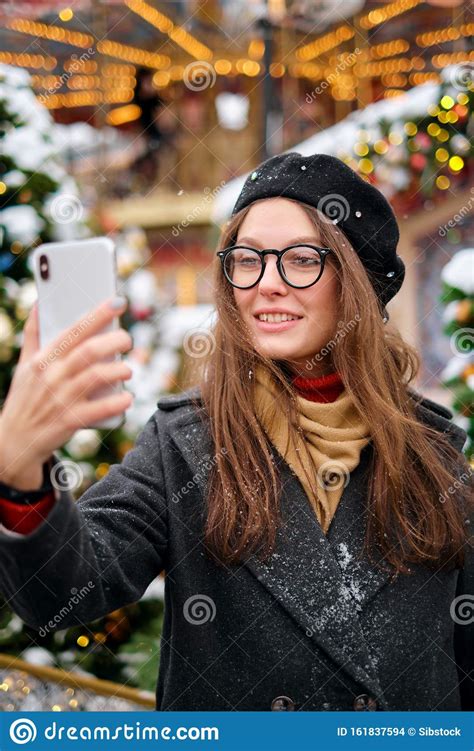 Beautiful Young Woman Taking A Selfie With Christmas Tree Behind Her