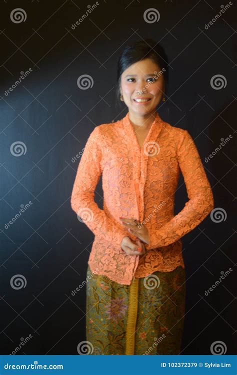 an indonesian woman wearing orange kebaya and batik sarong stock image