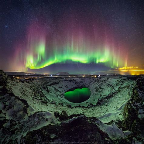 impresionante fotografia de una aurora boreal reflejada en  crater en islandia