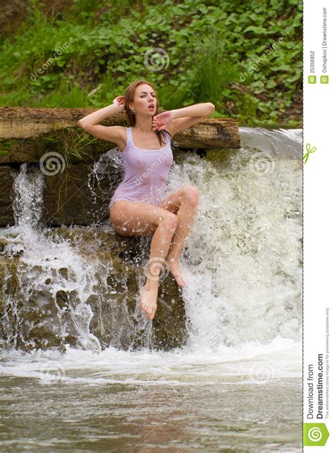 A Girl Dressed In White Sitting By A Waterfall Stock