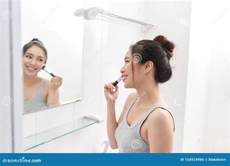 young woman  standing  front   bathroom mirror  putting