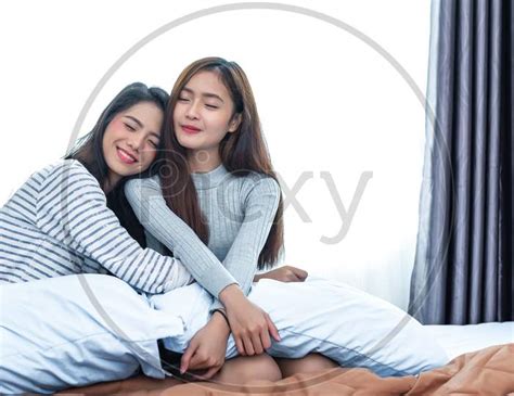 image of two asian lesbian women hug together in bedroom couple people
