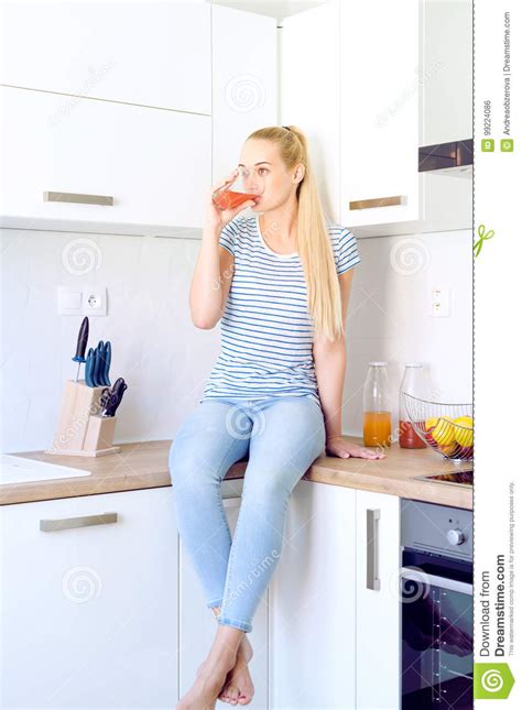 Woman Drinking Homemade Fruit Juice Sitting On Kitchen