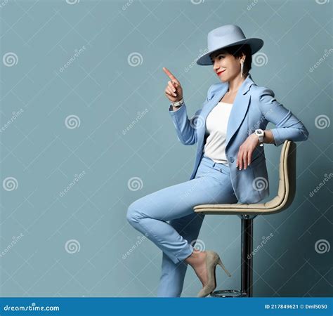 Slyly Smiling Short Haired Brunette Woman In Blue Business Suit And Hat